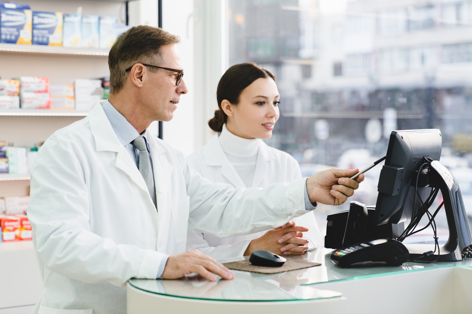 pharmacist-pointing-showing-male-colleague-medication-prices-prescriptions-on-computer-screen.jpg
